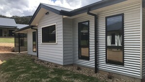A modern house with a sloped roof, large windows, and a covered porch area. - Bright Racecourse View #2 (Bright)