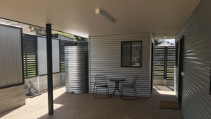 A covered outdoor patio area with metal walls, a table, and two chairs. - Bright Racecourse View #2 (Bright)
