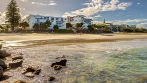 A beachfront hotel with multiple buildings, a sandy beach, and clear waters. - Kings Beach Top Floor Unit With Private Rooftop (Kings Beach)
