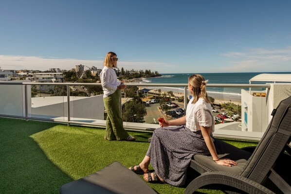 A balcony with artificial grass, a view of the sea, and a Ferris wheel in the distance. - Kings Beach Top Floor Unit With Private Rooftop (Kings Beach)