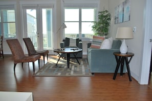 A living room with a sofa, two armchairs, a coffee table, a lamp, and a potted plant.