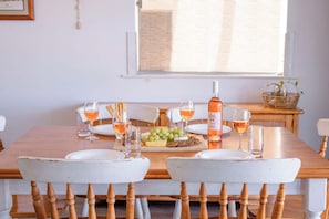 Une table à manger dressée avec des assiettes, des verres, une bouteille et un panier de raisins.