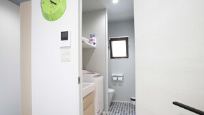 Un baño con inodoro, lavabo, espejo, reloj y ventana.