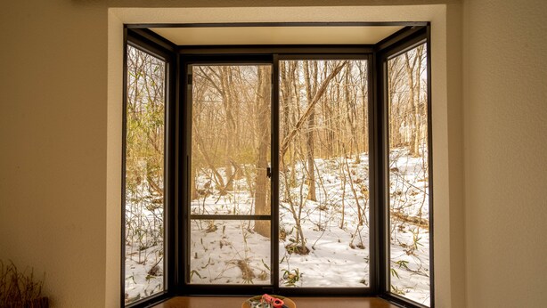 Quarto com uma grande janela com vista para uma paisagem nevada.