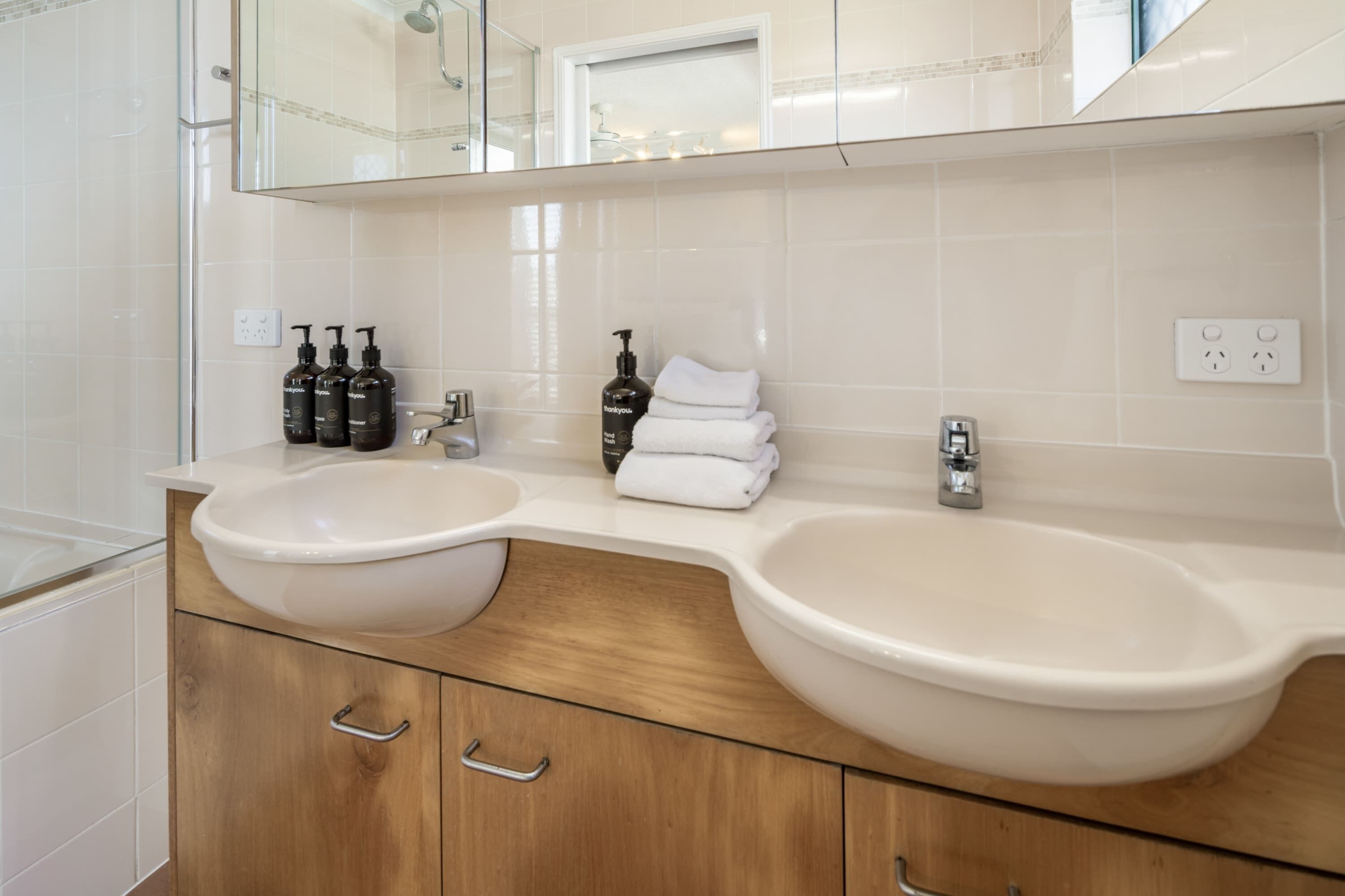 A bathroom with two sinks, a mirror, and a towel rack.