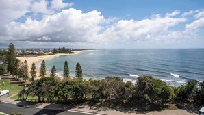 A coastal view with a beach, ocean, and residential area. - Oceanfront Views at Moffat Beach + Rooftop Terrace (Moffat Beach)