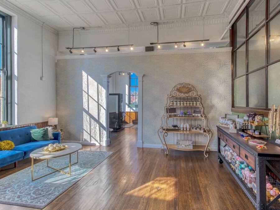 A spacious room with a blue sofa, a white coffee table, and a decorative metal shelf with various items.