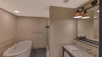 Un baño moderno con una bañera independiente, una ducha a ras de suelo y un tocador con un espejo grande.