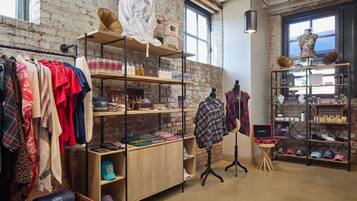 A clothing store with racks of clothes, shelves with hats, and a mannequin.
