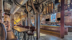 A rustic bar area with exposed brick walls, wooden bar counter, and seating with stools. - The Sessions Hotel, Bristol, a Tribute Portfolio Hotel (Bristol)