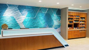 Zona de recepción con un mostrador de madera, una pared con texto y un estante con aperitivos.