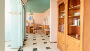 A hallway with a checkered floor, wooden furniture, and a large wooden bookcase.