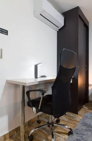 Un espacio de oficina moderno con escritorio, silla y unidad de aire acondicionado.