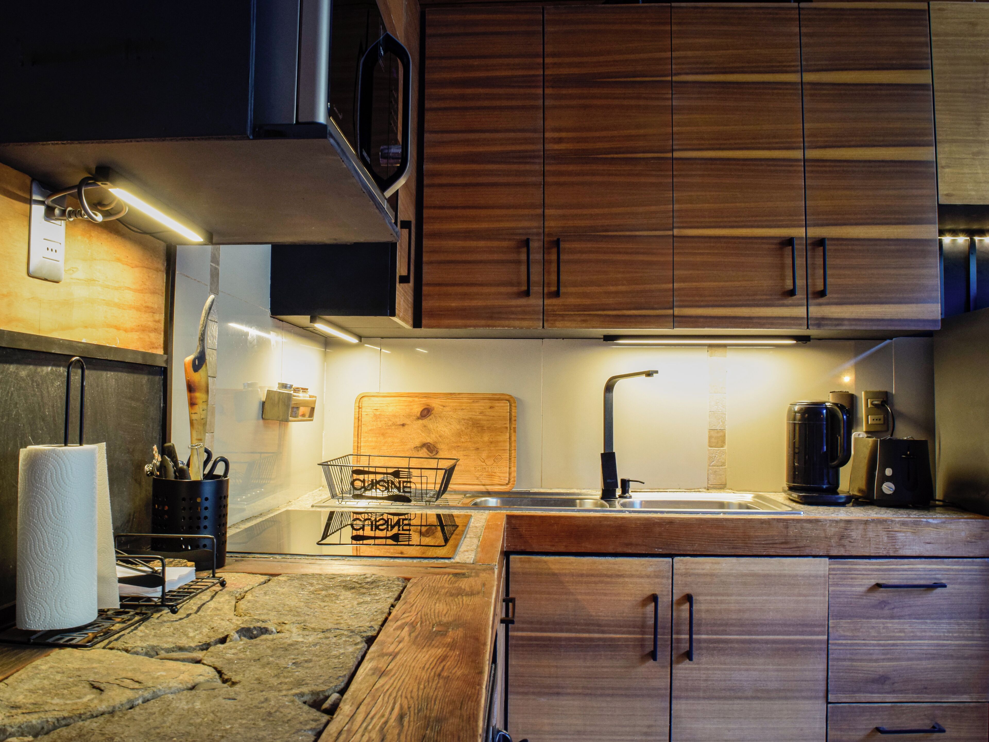 A modern kitchen with wooden cabinets, a stainless steel sink, and a coffee maker.