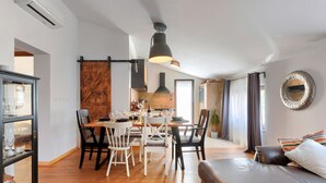 Uma sala de jantar com mesa de madeira, cadeiras e luminária pendente.