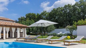 Uma piscina com espreguiçadeiras e um guarda-sol.