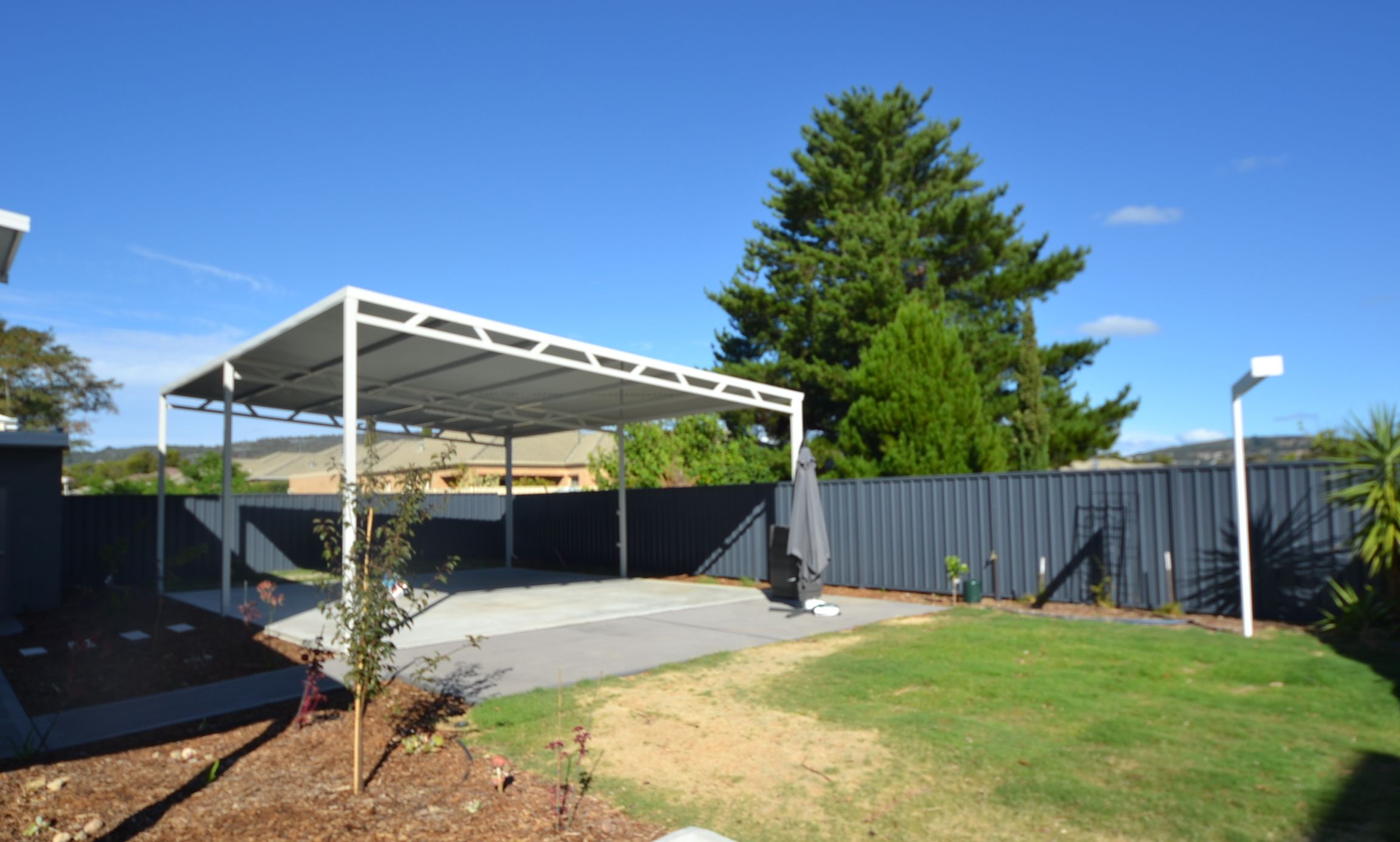 A covered outdoor area with a lawn and trees.