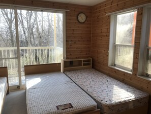 Una habitación con una cama, un reloj y ventanas amplias.