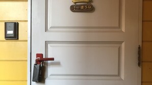 Una puerta blanca con picaporte rojo y cerradura con llave.