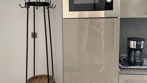 Una cocina con un refrigerador de acero inoxidable, un microondas y una cafetera sobre la encimera.