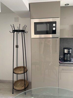 Een keuken met een roestvrijstalen koelkast, een magnetron en een koffiezetapparaat op het aanrecht.