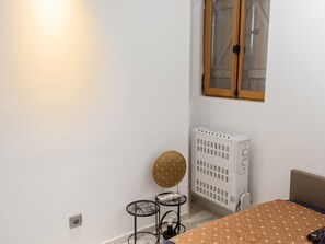 A room with a white wall, a radiator, a window with wooden frames, and a table with a patterned tablecloth. - Homerez - Cozy House in Cirey-sur-Vezouze (Cirey-sur-Vezouze)