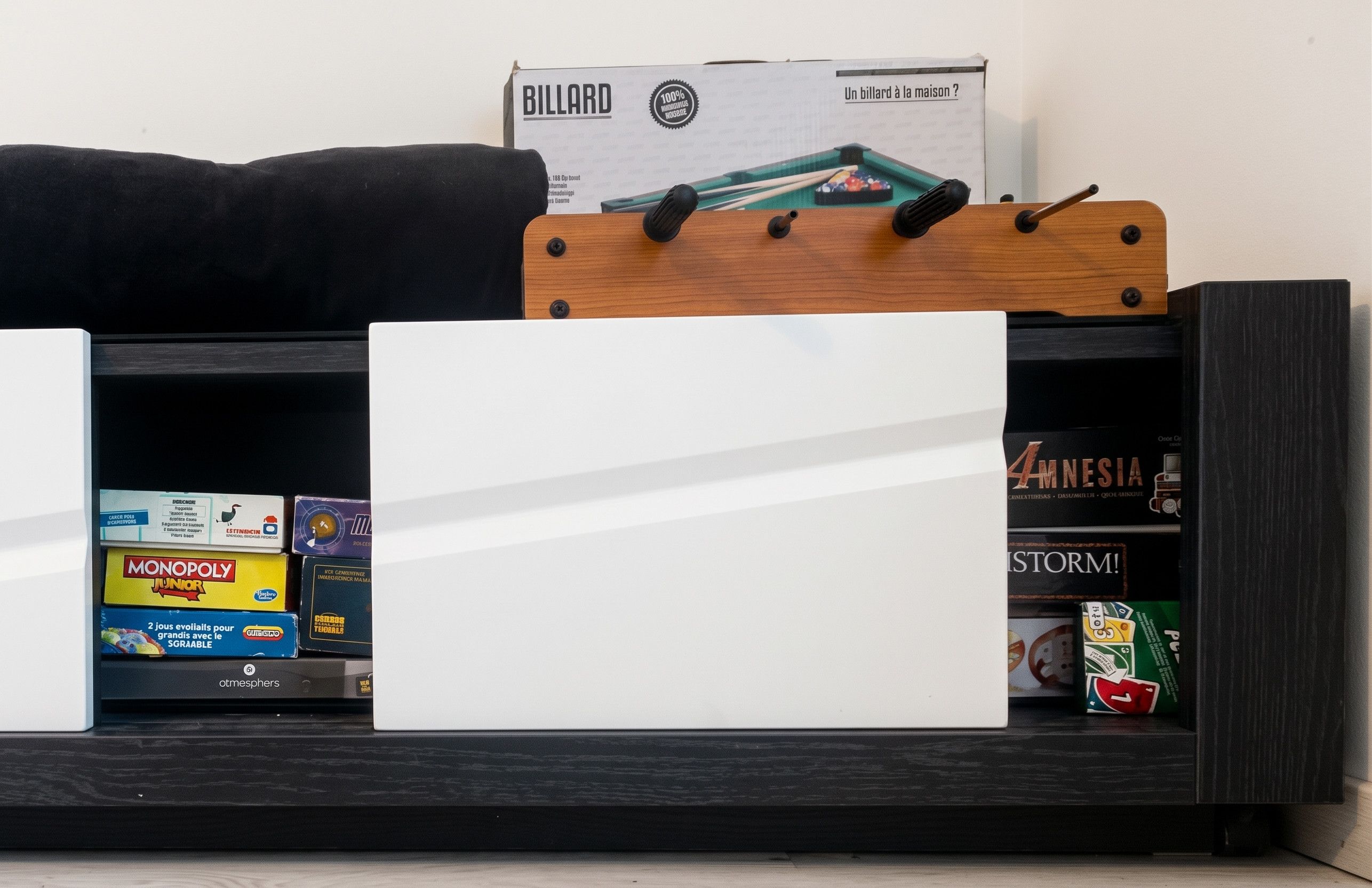 A shelf with various board games and a billiard table box.