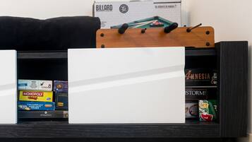 A shelf with various board games and a billiard table box.