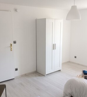 Ein Zimmer mit einem weißen Kleiderschrank, einer Tür und einer Pendelleuchte.