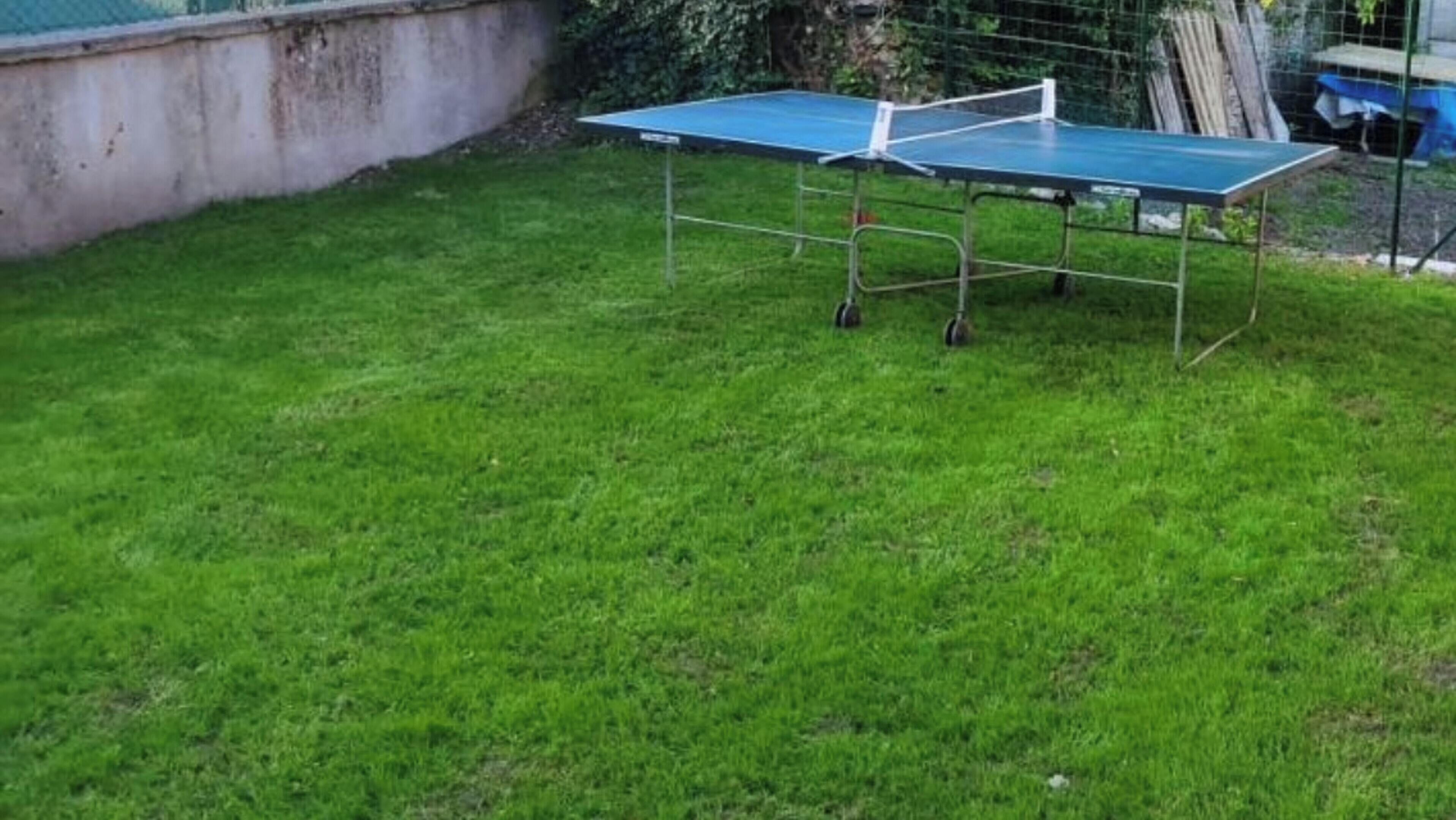 A ping pong table in a grassy outdoor area.