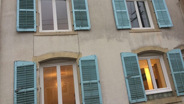 Un edificio con múltiples ventanales, algunos con contraventanas, y un estilo arquitectónico uniforme.