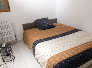 Un lit simple avec une couvre-lit à motifs, un oreiller et une table de chevet avec une lampe.
