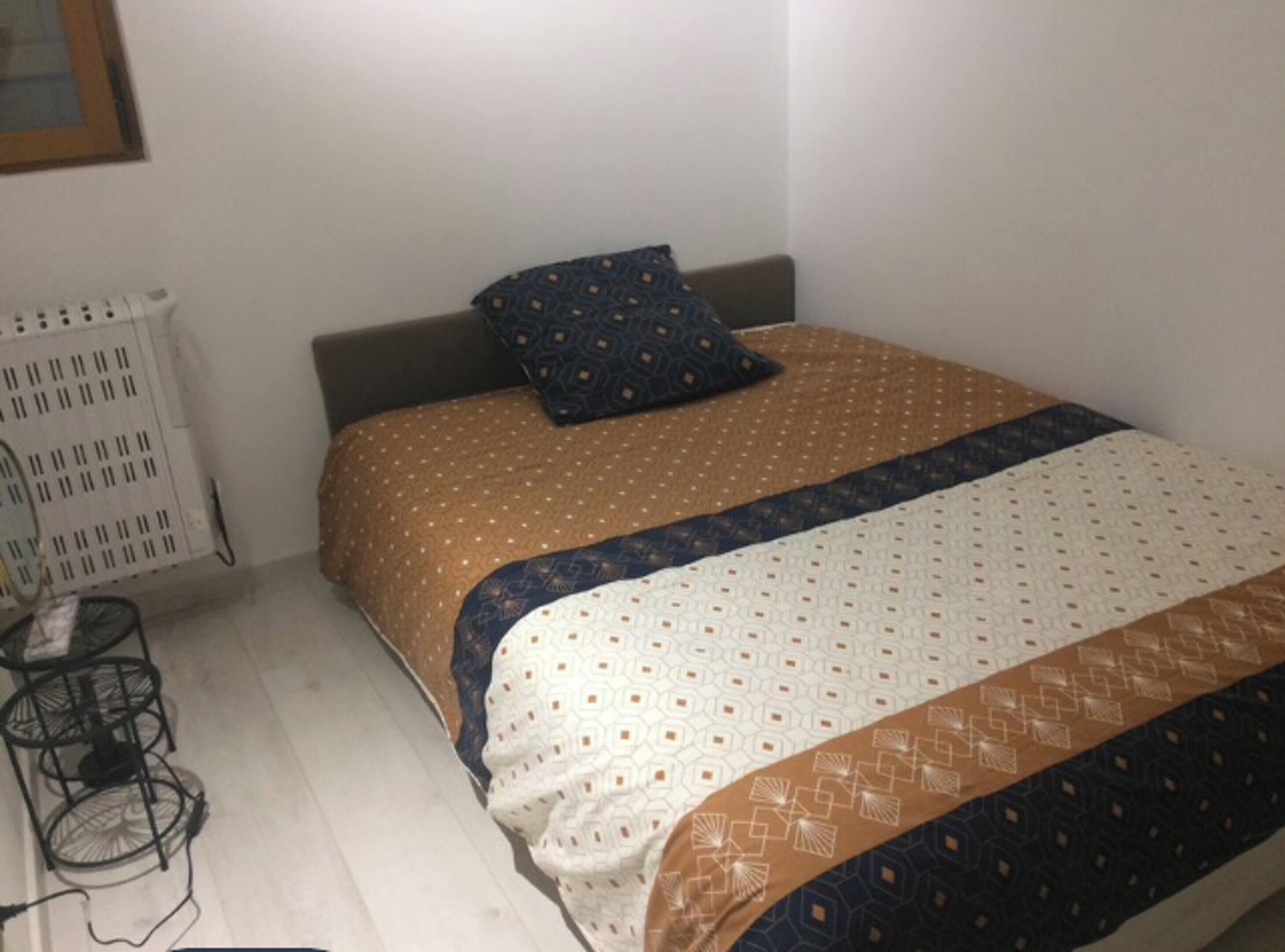 Een kleine, verzorgde slaapkamer met een enkel bed, nachtkastje en radiator.