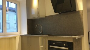 Una cocina con ventana, horno empotrado y microondas.