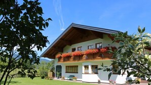 Ein zweistöckiges Haus mit geneigtem Dach, Holzbalustraden und Blumenkästen im zweiten Stock.