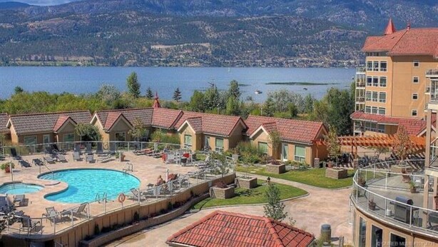 A hotel with a pool, outdoor seating, and a view of a lake and mountains. - Tranquil Waterfront Condo (Kelowna)