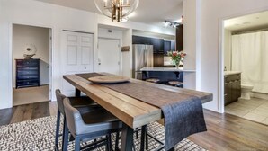 A modern kitchen with a wooden table, black chairs, and a pendant light. - Tranquil Waterfront Condo (Kelowna)