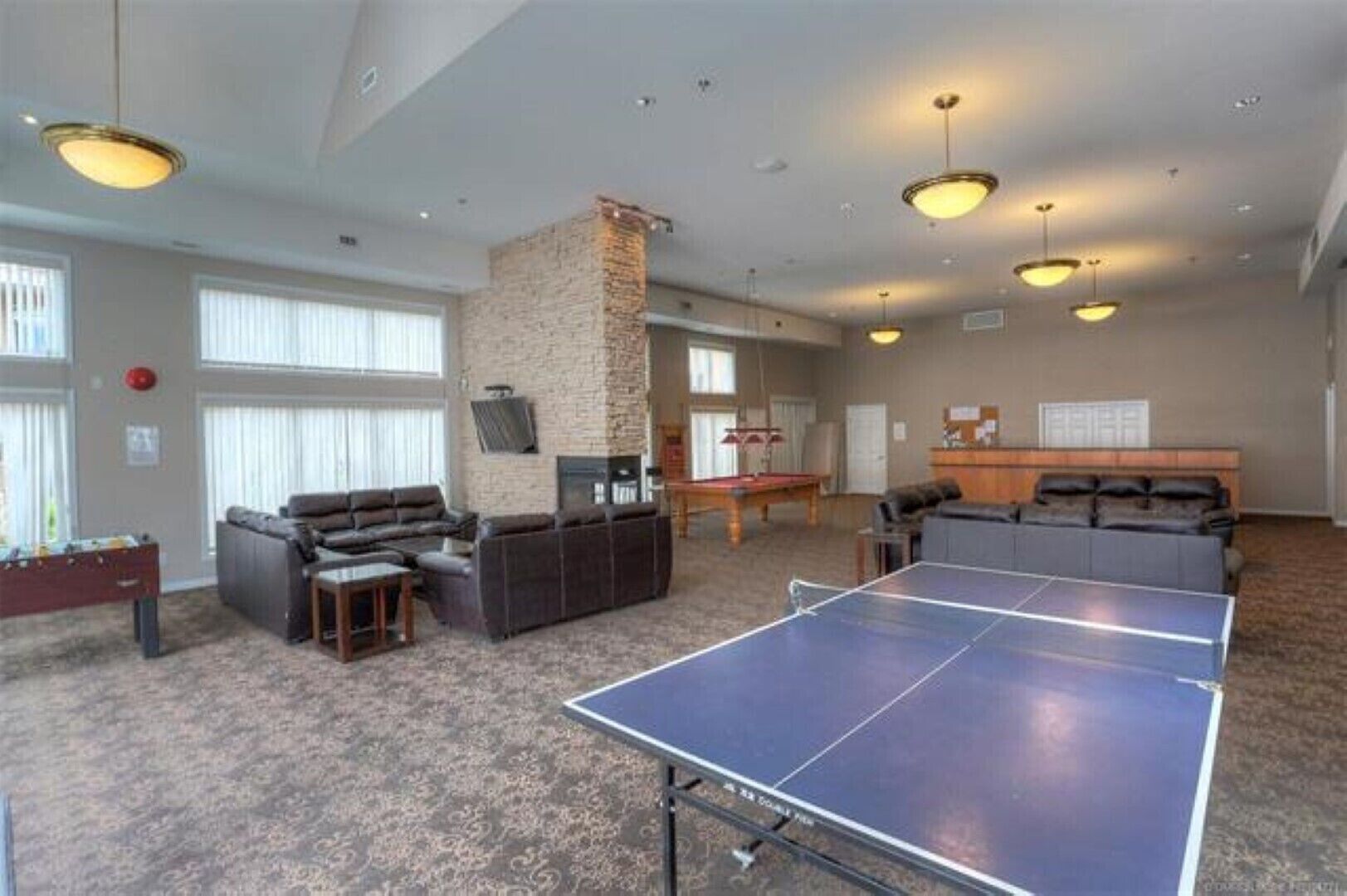 A spacious indoor area with a ping pong table, sofas, and a pool table.