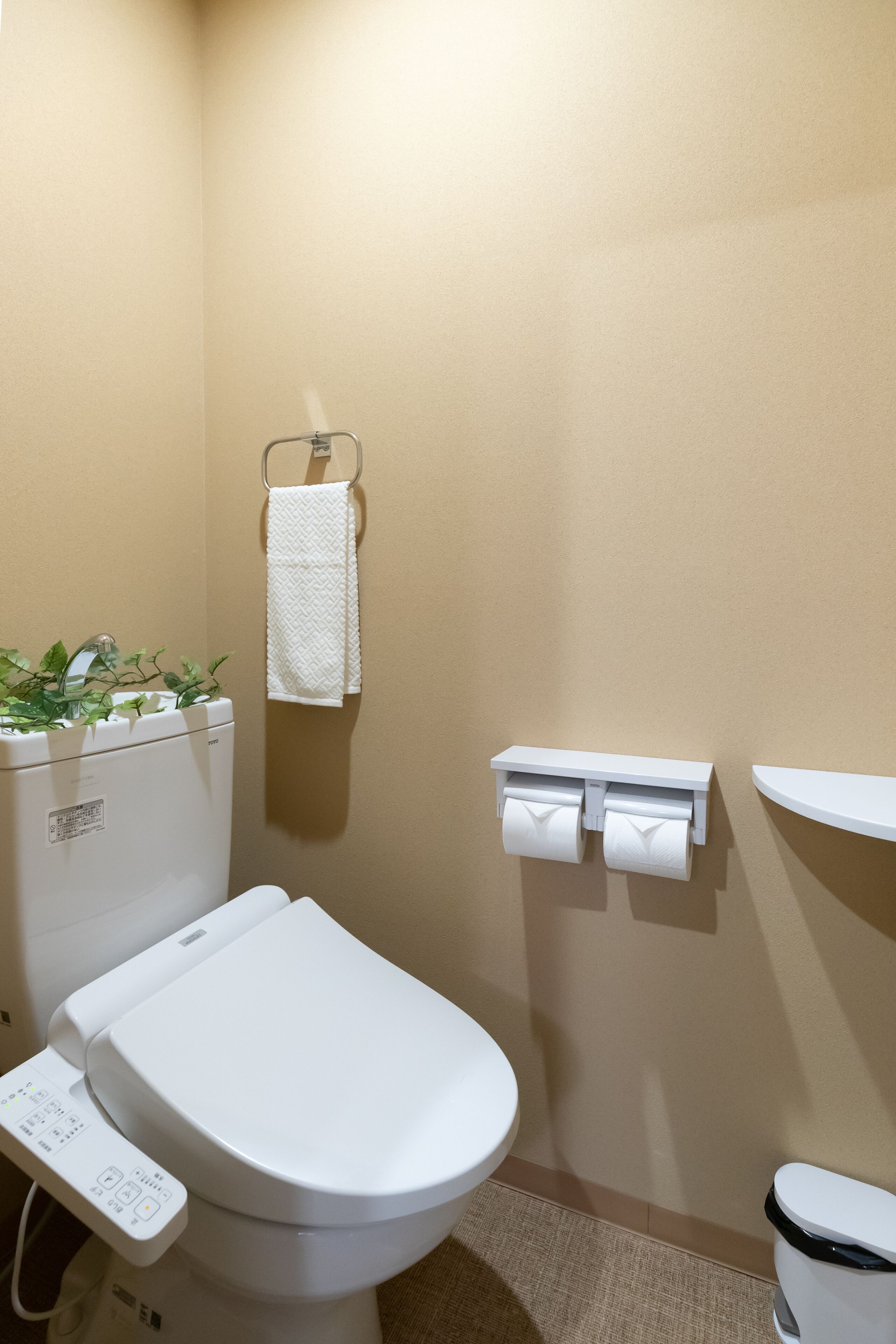Une salle de bain moderne équipée d’un WC, d’un lavabo, d’un porte-serviettes et d’un support à papier toilette.