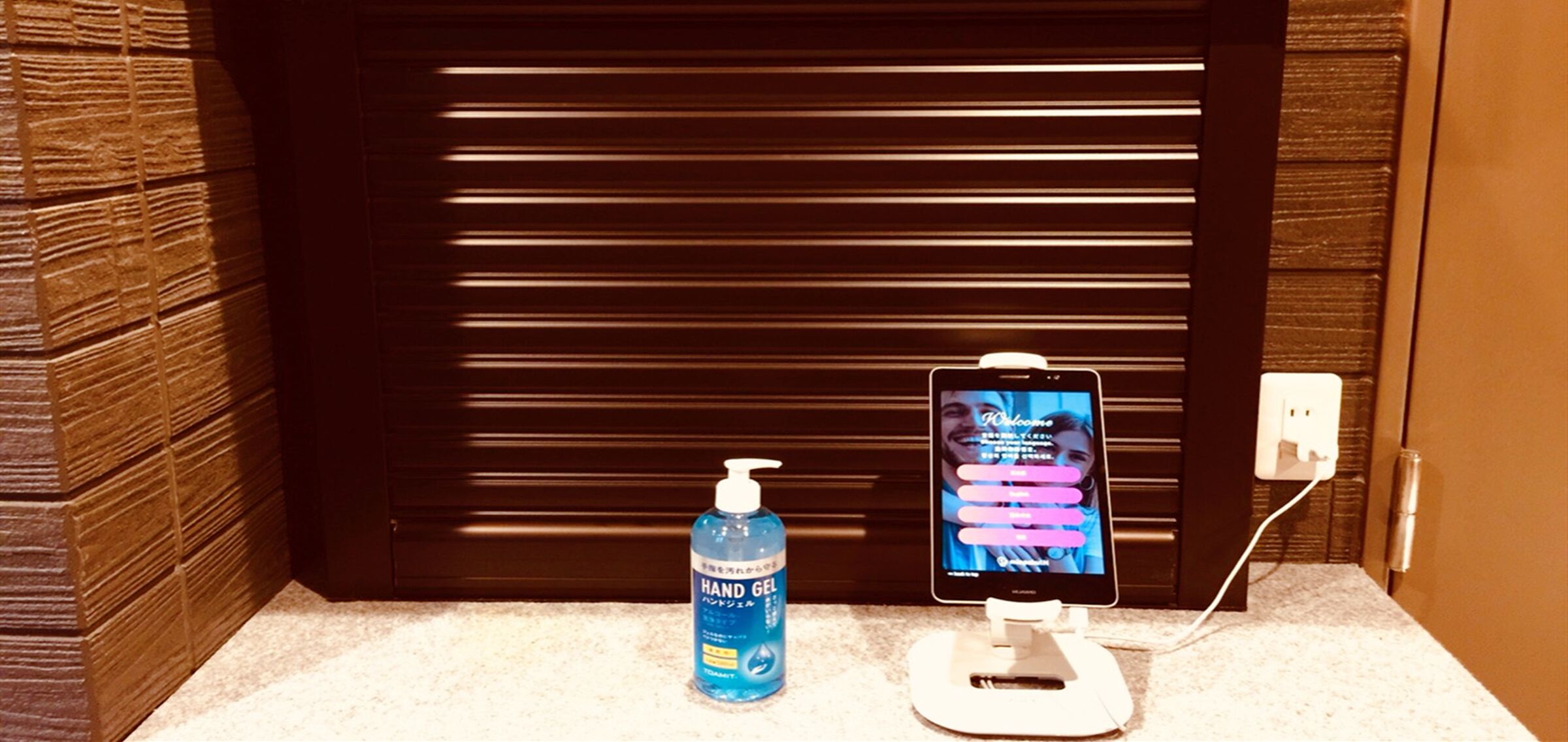 Una botella de gel hidroalcohólico y un teléfono móvil cargando sobre una encimera.