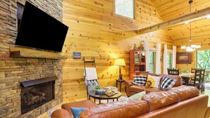 Un intérieur de chalet chaleureux avec une cheminée en pierre, un canapé en cuir et des murs en bois.