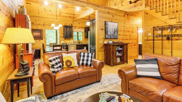 L’intérieur chaleureux d’un chalet en bois comprend un salon avec des canapés en cuir, un coin repas et une cuisine.