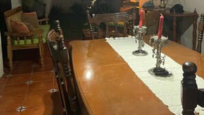Uma sala de jantar com mesa de madeira, cadeiras e um candelabro.