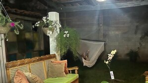 Uma área de pátio aconchegante com um sofá de madeira, uma cadeira suspensa e uma mesinha.