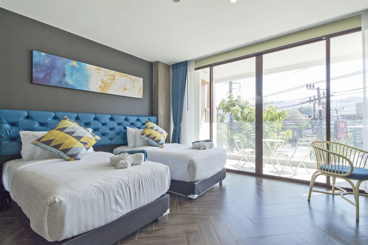 Une chambre d’hôtel avec deux lits, une grande fenêtre et une vue sur la ville.
