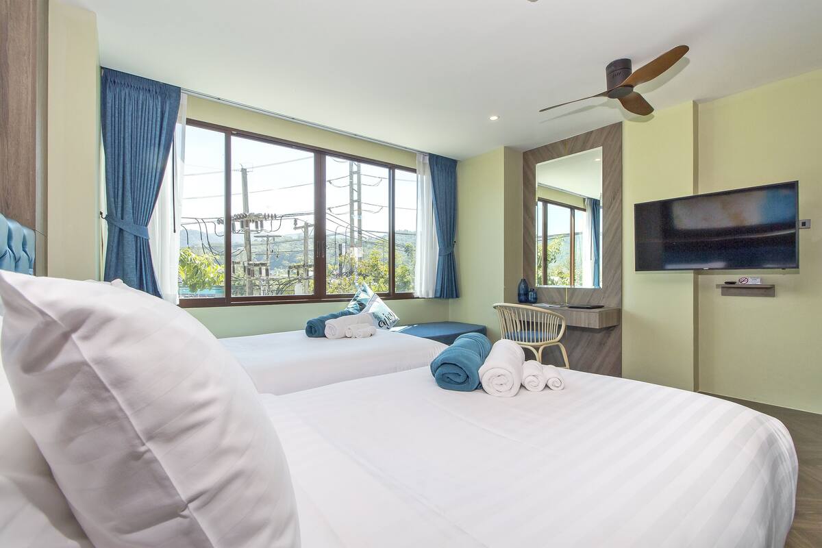 Une chambre d’hôtel avec deux lits, un bureau, une chaise, une télévision et une vue sur l’extérieur.