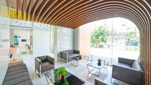 Un vestíbulo moderno con techo de madera curva, paredes de vidrio y zonas de descanso.