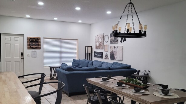 A modern kitchen with a dining area, featuring a wooden table, black chairs, and a blue sofa.