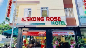 Exterior del hotel Mekong Rose, con un letrero llamativo, escaparate con flores y una entrada visible.
