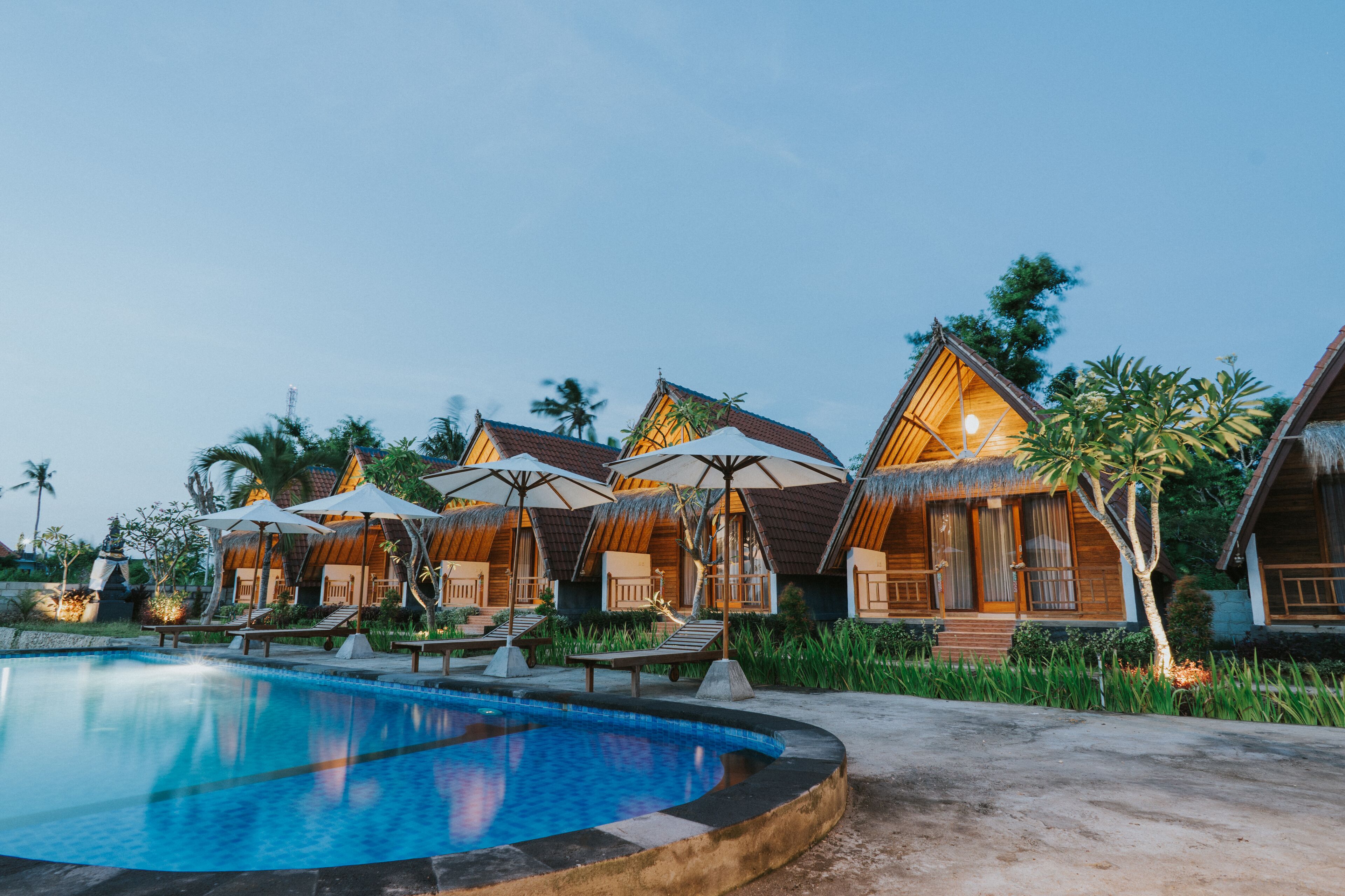 A resort with thatched-roof cottages, a swimming pool, and outdoor seating areas.
